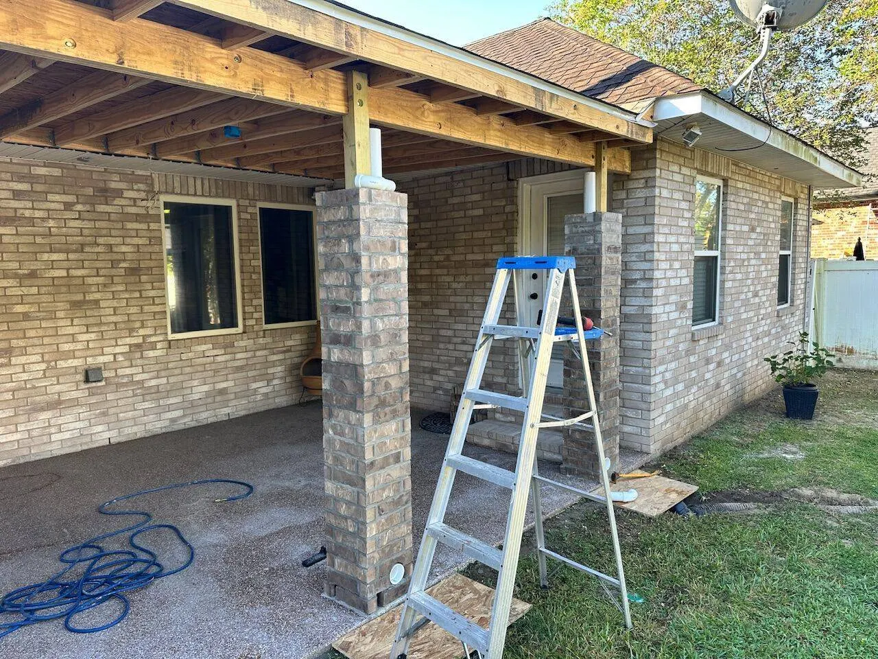 Covered patio framing with brick columns and pressure-treated lumber on residential home