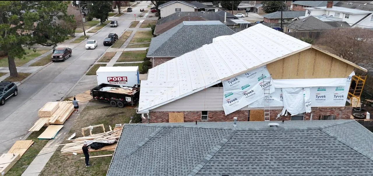 Aerial street view of second floor addition with Tyvek wrap and crew working in Metairie
