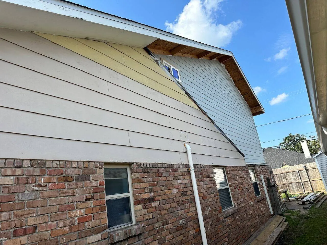 Second story addition exterior showing new siding installation over brick on Louisiana home
