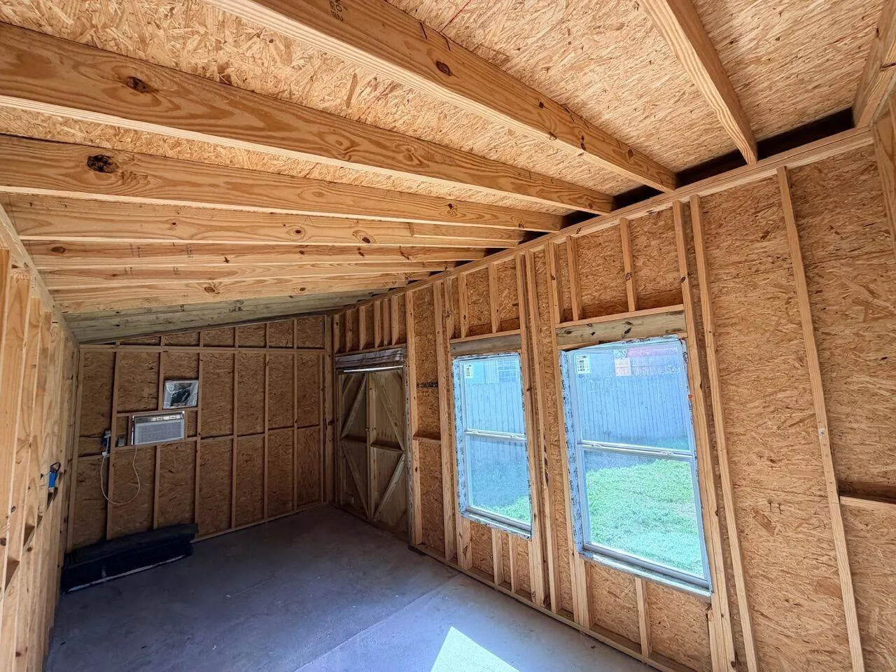 Interior framing of new construction shed showing rafters and AC unit in Meraux Louisiana