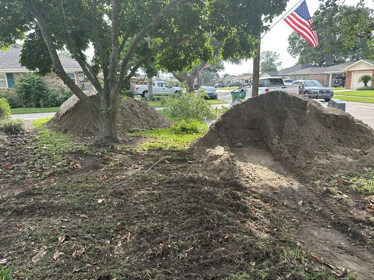 Excavated dirt piles staged in front yard during site preparation for new construction in Metairie neighborhood
