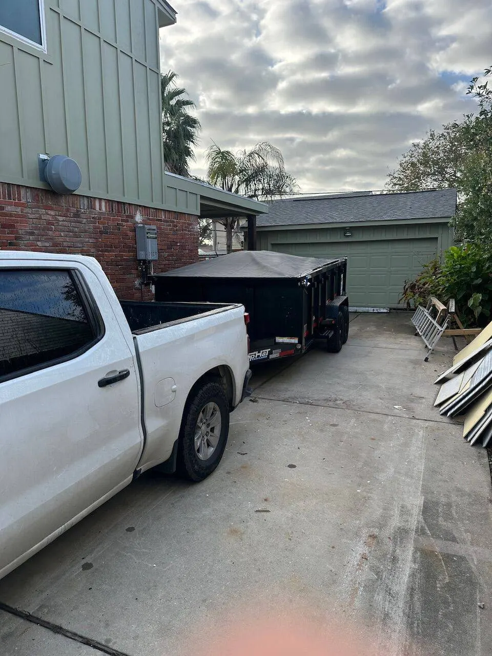 Cajun Home Services work truck and dump trailer at active construction jobsite in Metairie