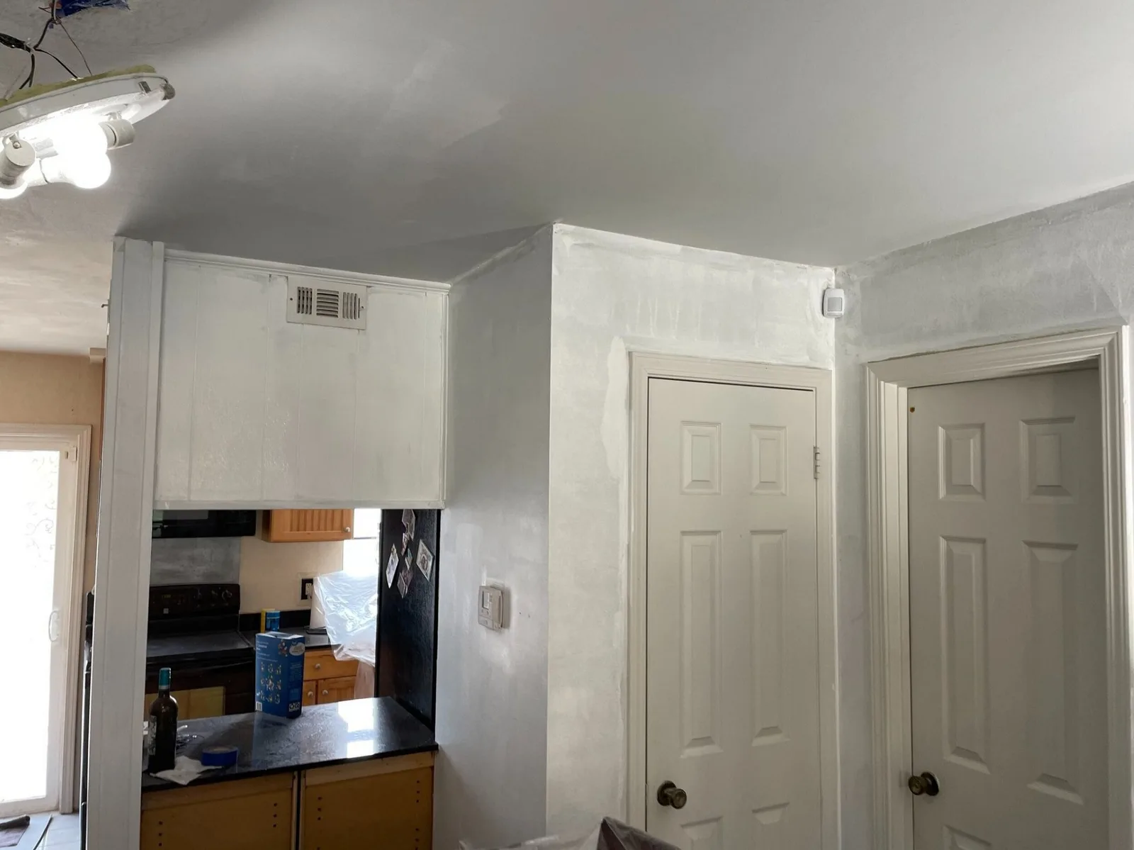 Gretna LA kitchen and laundry corner after popcorn ceiling removal and full skim-coat, freshly primed walls and ceiling with original cabinets and doors masked for paint by Cajun Home Services