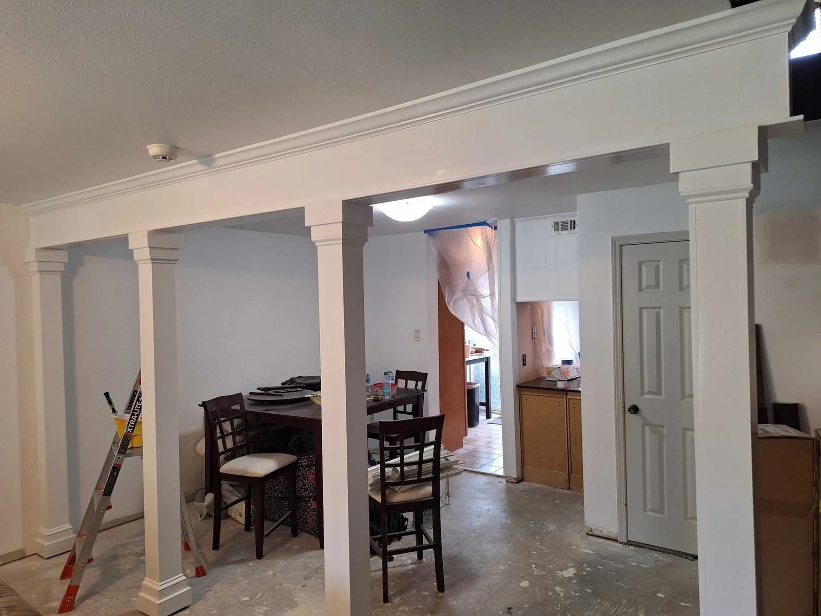 Gretna LA open living and dining area with newly installed custom column wraps, decorative crown caps and base trim creating an architectural divider between rooms — mid-remodel by Cajun Home Services