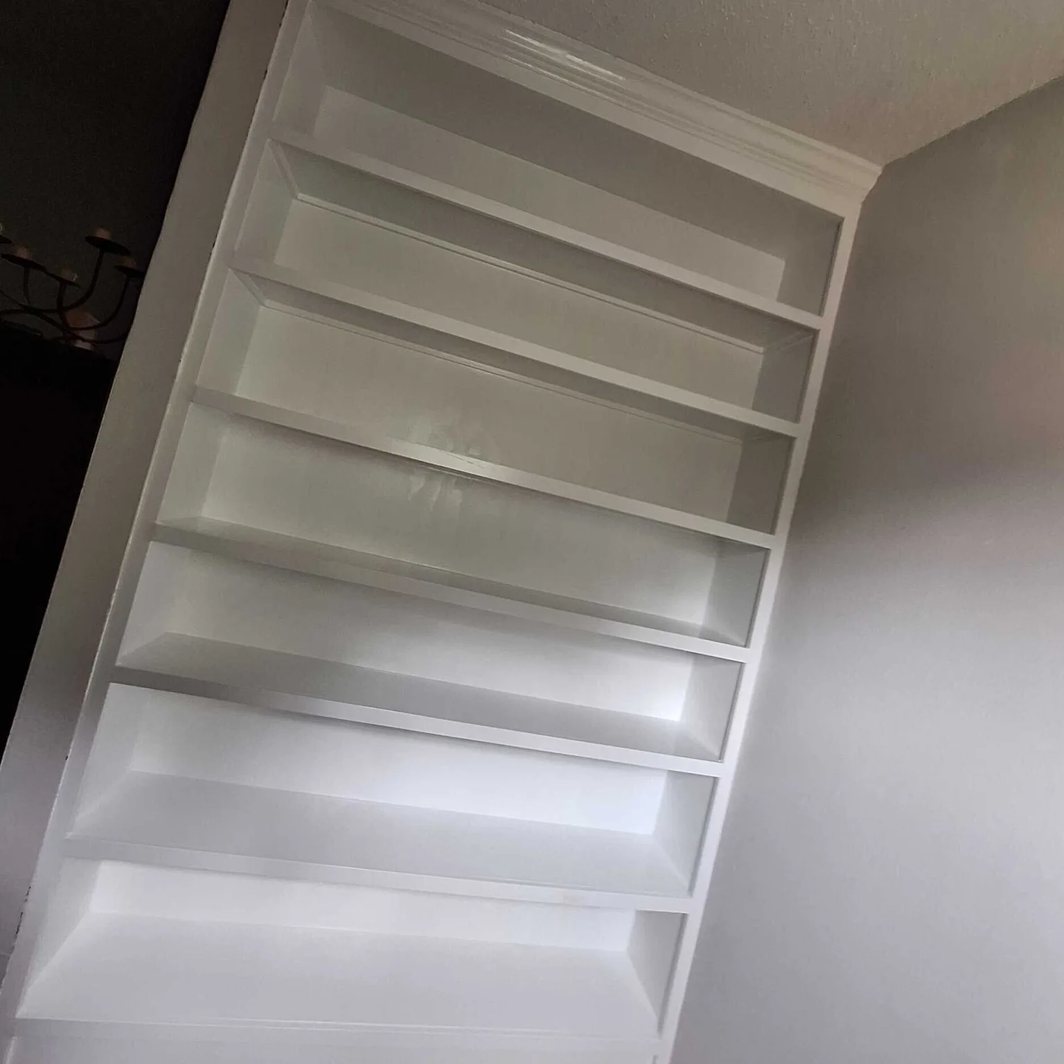 Gretna LA finished floor-to-ceiling custom built-in bookshelf with crown moulding cap and bevelled shelves painted high-gloss white — carpentry detail by Cajun Home Services interior remodel team