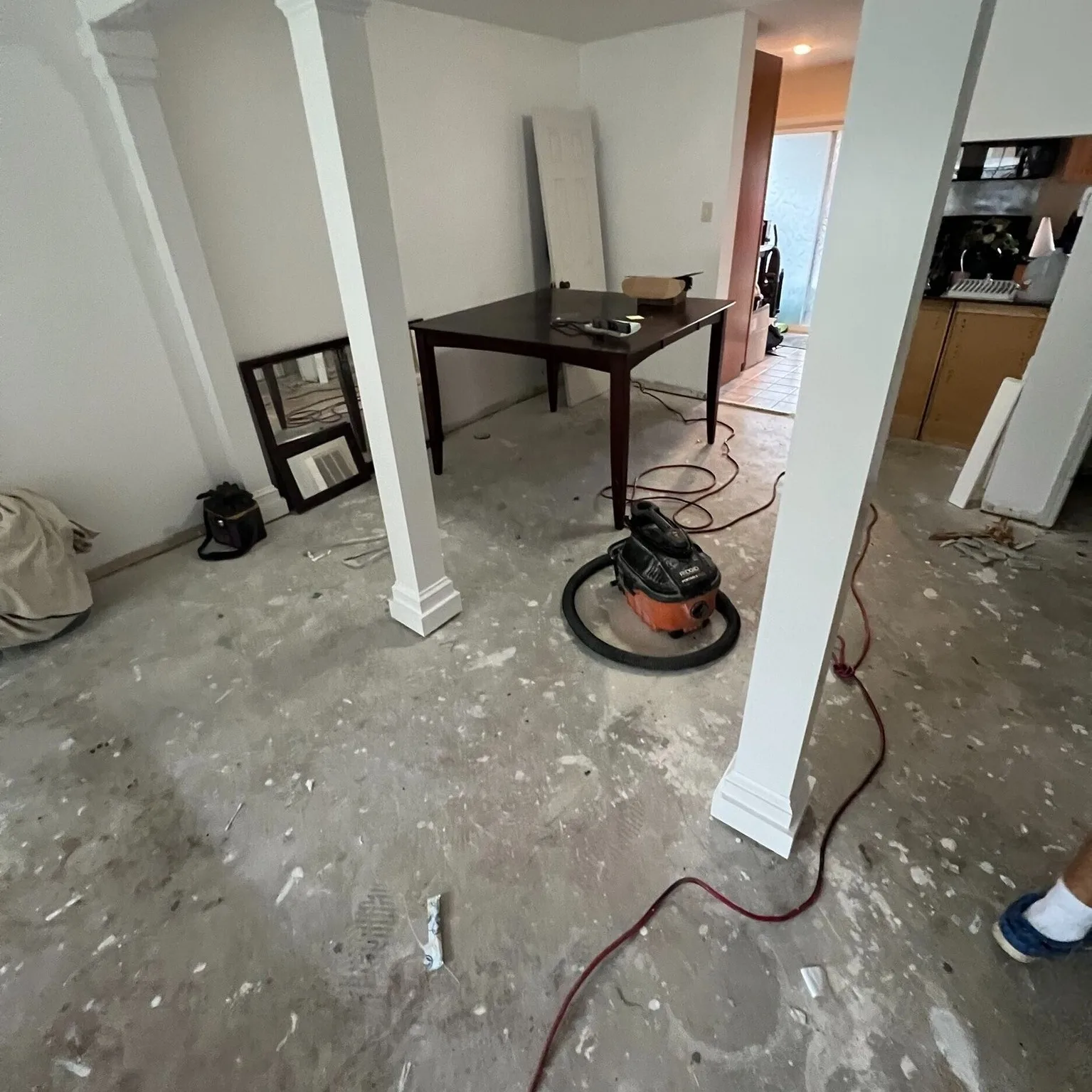 Gretna LA living and dining area after demo with bare concrete subfloor swept clean, custom column wraps fully trimmed and painted, ready for new LVP flooring installation by Cajun Home Services