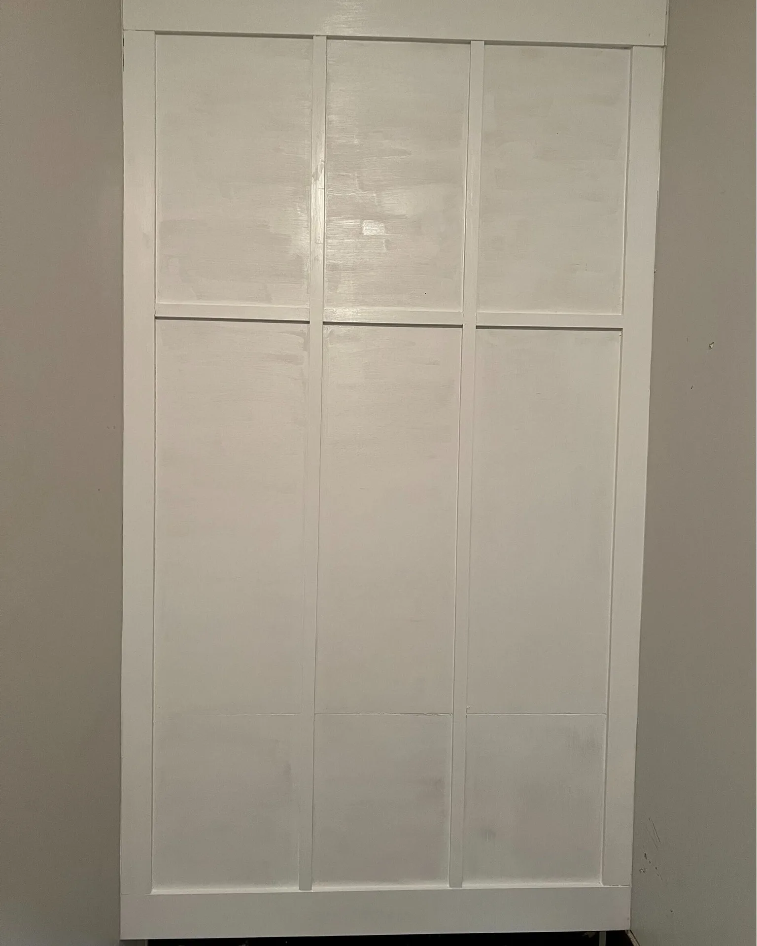 Gretna LA tall accent wall finished in custom board-and-batten with six rectangular bays painted smooth high-gloss white, transforming a blank corner into a decorative architectural feature by Cajun Home Services