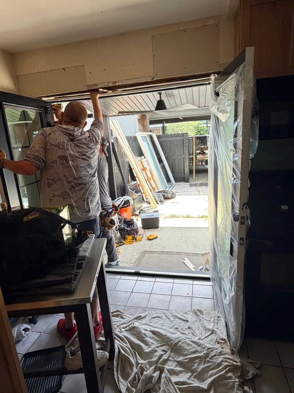 Gretna LA kitchen back patio door opening with Cajun Home Services carpenter installing new ProVia French doors, header framing exposed above and old slider removed during full door replacement