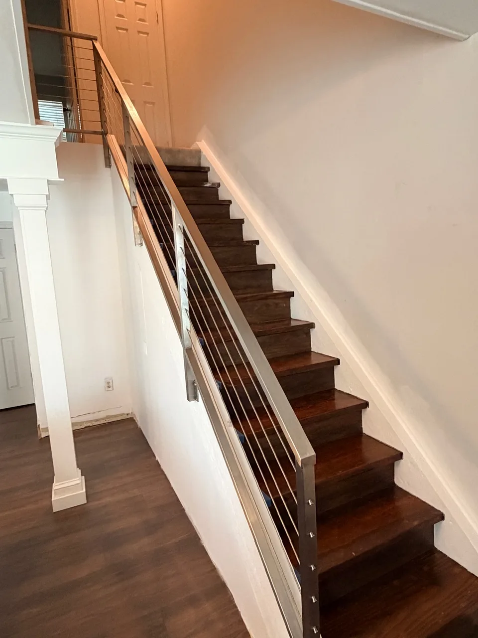 Gretna LA finished open stairwell with refinished walnut treads, white risers, and full-height stainless steel cable railing leading up to second floor — completed remodel by Cajun Home Services