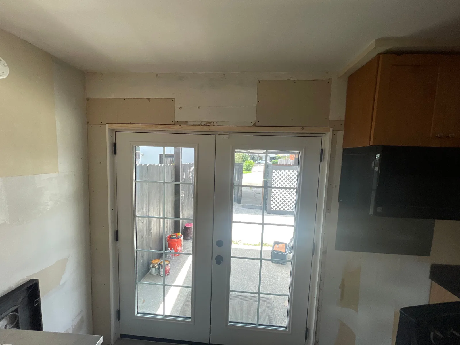 Gretna LA kitchen back wall with newly installed white ProVia French doors set into framed opening, surrounding drywall patches taped and ready for mud and paint by Cajun Home Services