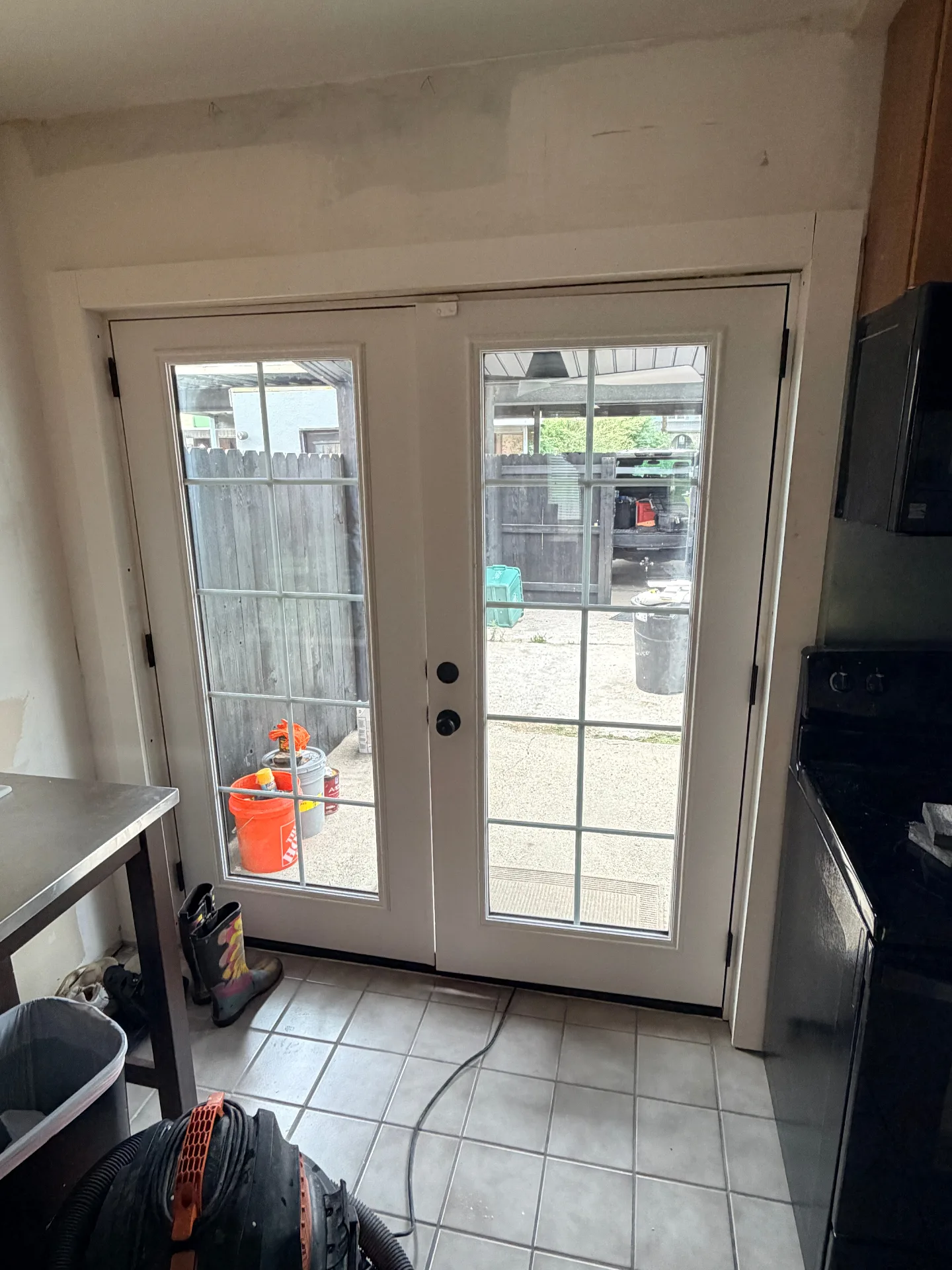Gretna LA kitchen back ProVia French doors fully installed and trimmed with black handle hardware and matte black hinges, surrounding drywall floated smooth and primed and ready for final paint by Cajun Home Services