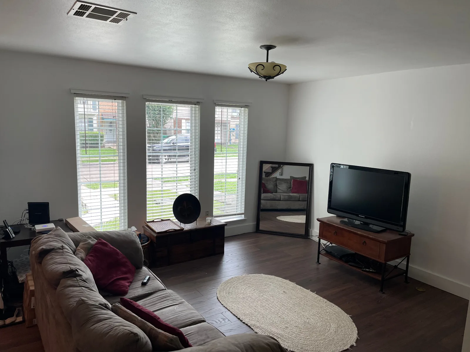 Gretna LA finished front living room with three bay-window openings, fresh white walls and trim, dark walnut LVP flooring and clean ceiling lines — completed remodel by Cajun Home Services