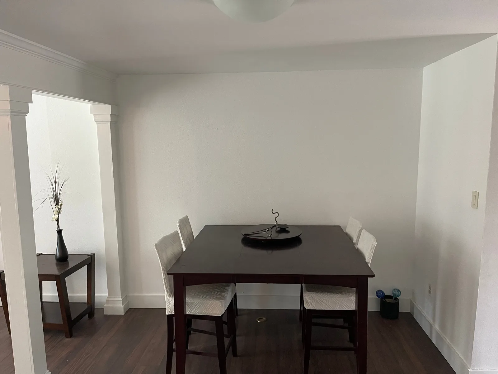 Gretna LA finished dining area with smooth painted walls, crisp white craftsman trim around the wide cased opening, and dark walnut LVP flooring — completed interior remodel by Cajun Home Services
