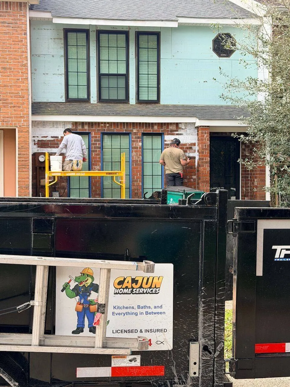Cajun Home Services branded trailer with crew working on exterior renovation make-ready