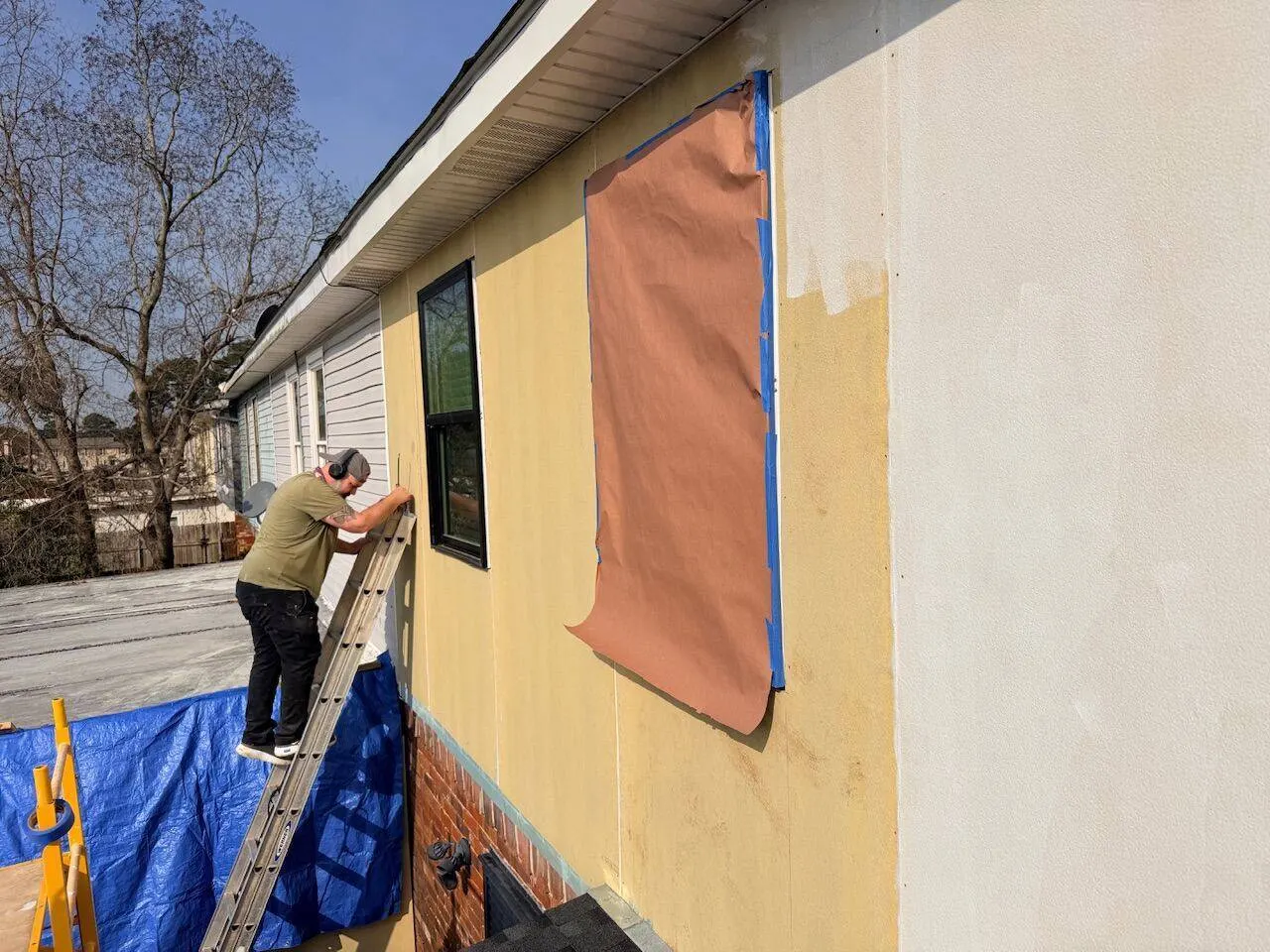 Crew painting exterior from yellow to white during pre-sale make-ready service