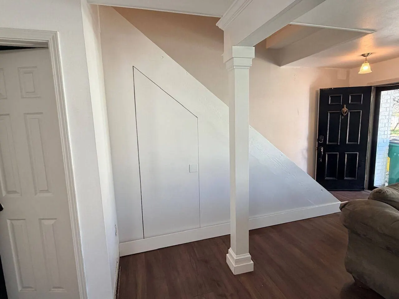 Custom under-stair storage with flush door and decorative column in renovated living room