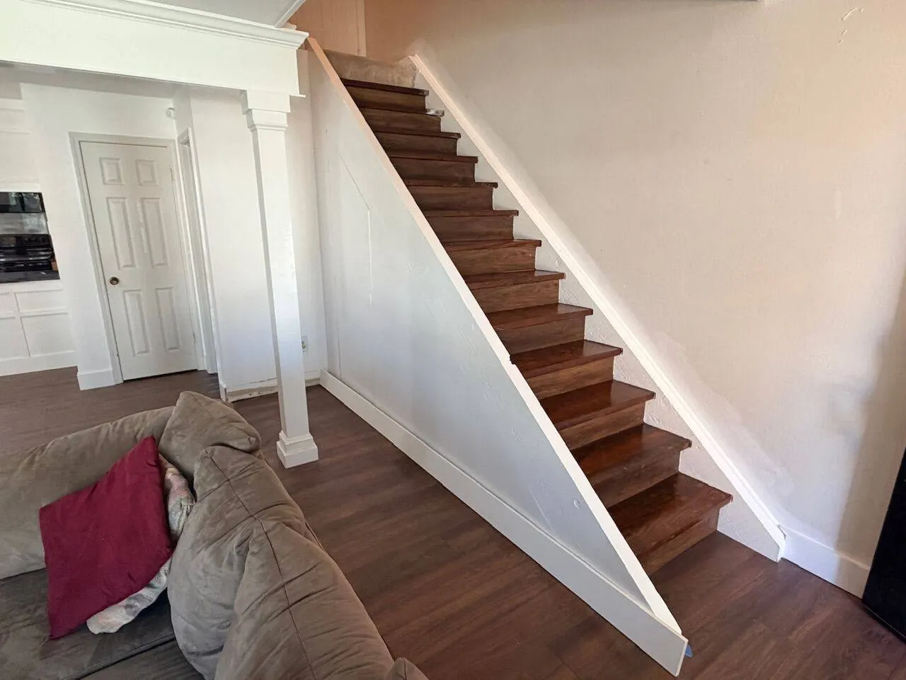 Finished staircase with stained hardwood treads and white painted stringers in whole home remodel
