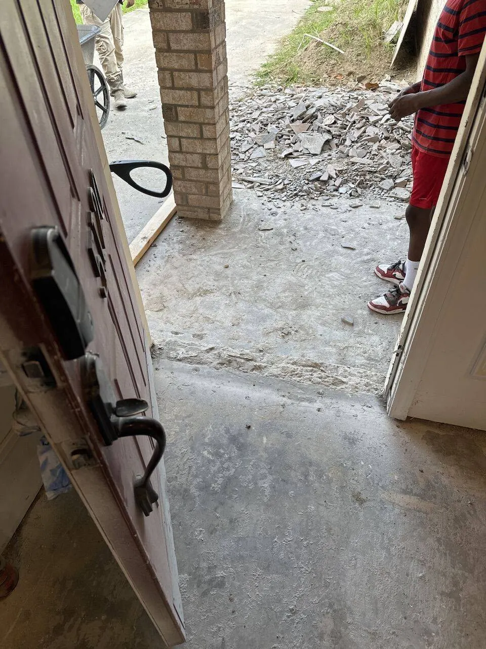 Crew removing old tile from front porch with debris pile during whole home renovation in Metairie
