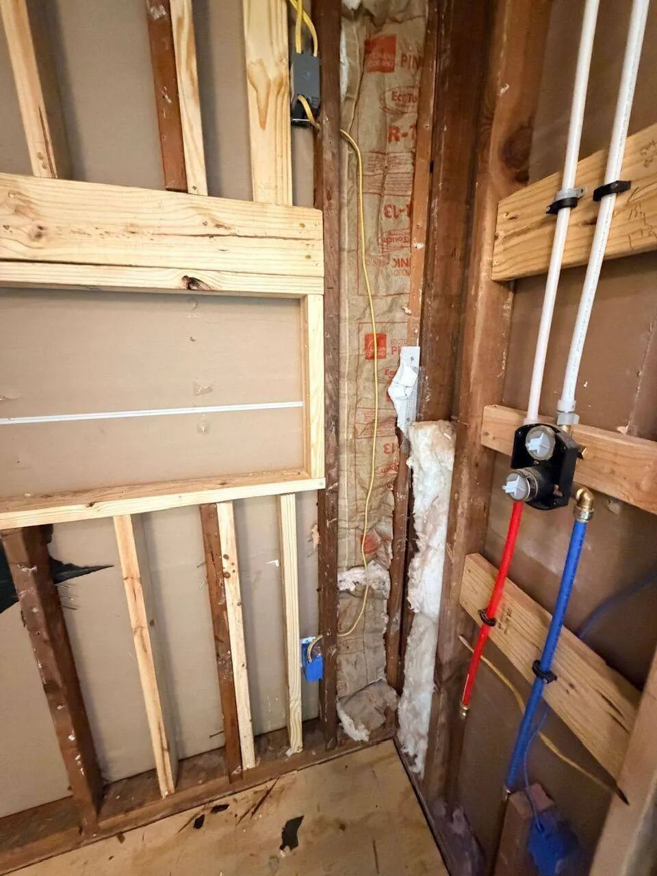 Bathroom wall framing with PEX hot and cold lines and shower mixing valve rough-in during remodel