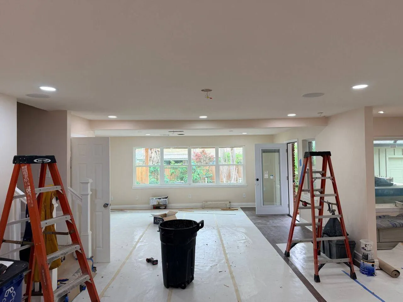 Open-concept interior renovation in progress with recessed lighting ladders and floor protection during whole home remodel in Southeast Louisiana