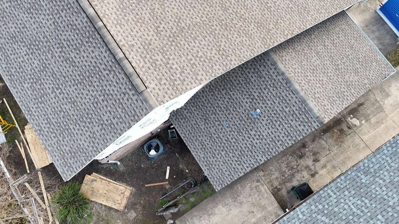 Aerial drone view of completed shingle roof showing valley detail and partial underlayment section
