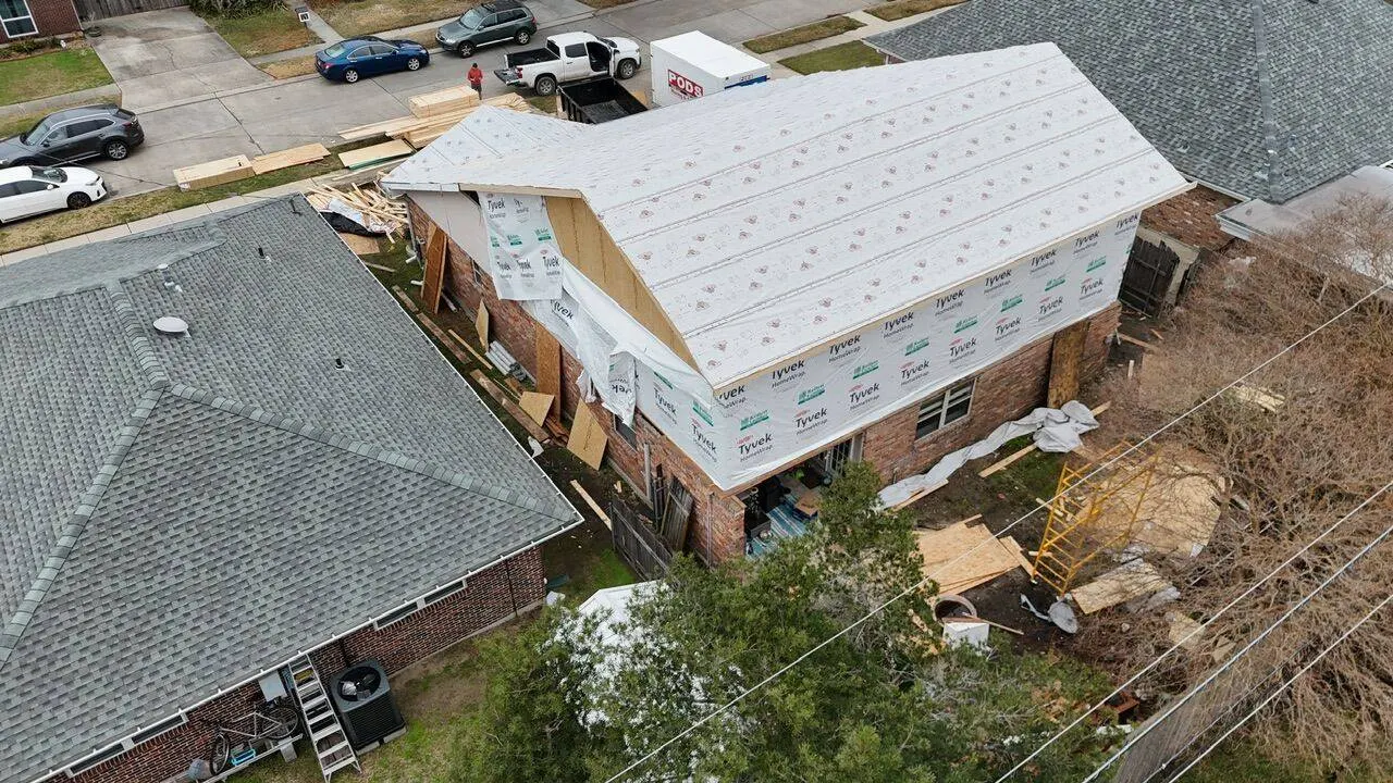 Aerial drone view of home addition wrapped in Tyvek housewrap with new roof framing in Metairie Louisiana