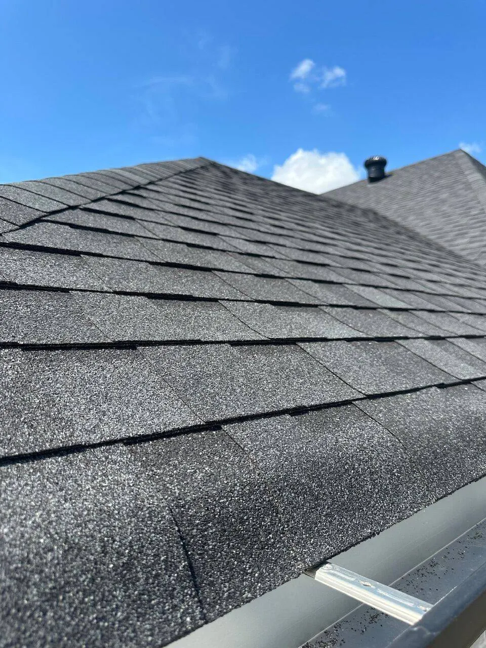 Close-up detail of dark charcoal architectural shingles showing texture and ridge cap on Louisiana home