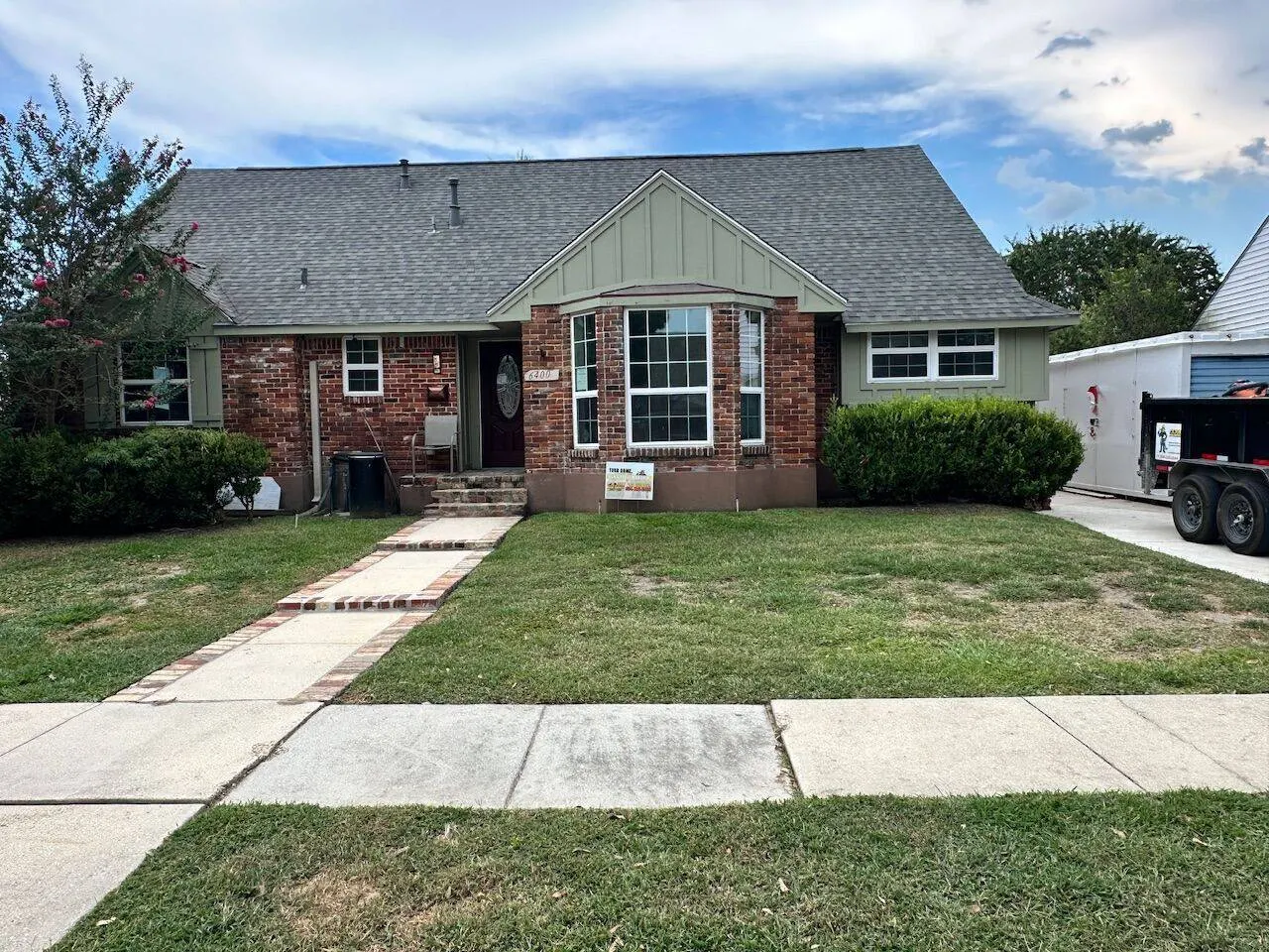 Completed shingle roof on brick home with Cajun Home Services yard sign in Metairie Louisiana