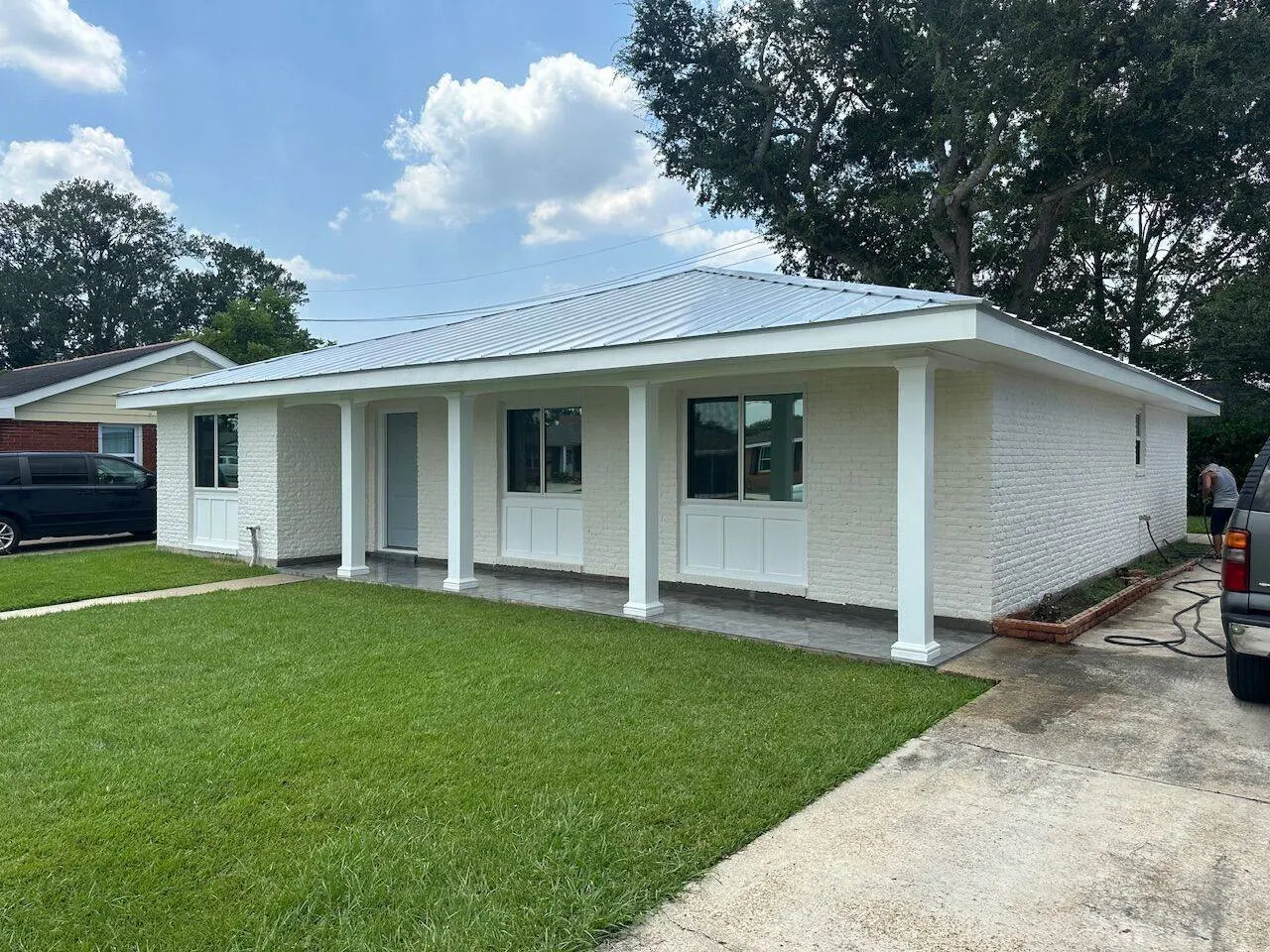 Completed standing seam metal roof on painted white brick home with covered porch in Metairie Louisiana