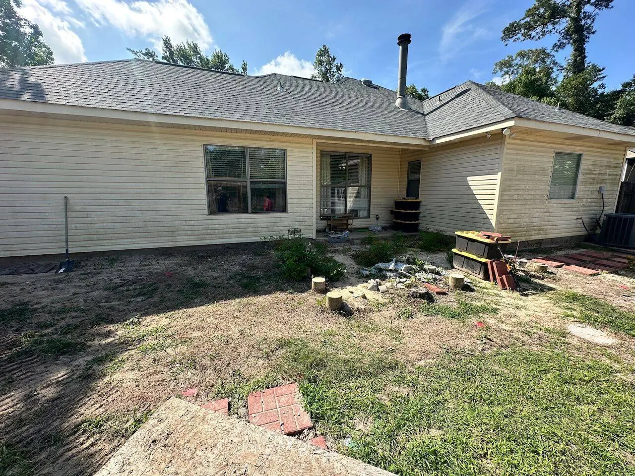 Rear view of completed shingle roof replacement on siding home in Louisiana showing clean ridge and chimney pipe