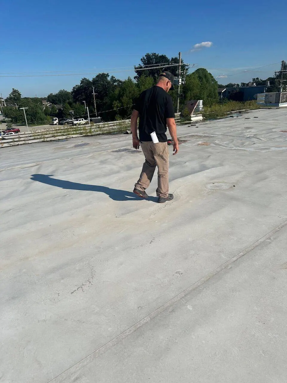 Cajun Home Services inspector walking commercial flat roof during assessment in Metairie Louisiana