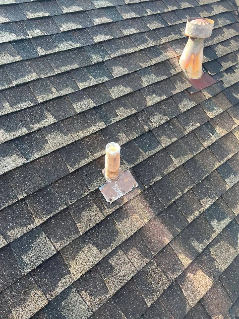 Close-up of vent pipe boots and plumbing penetrations on architectural shingle roof in Louisiana