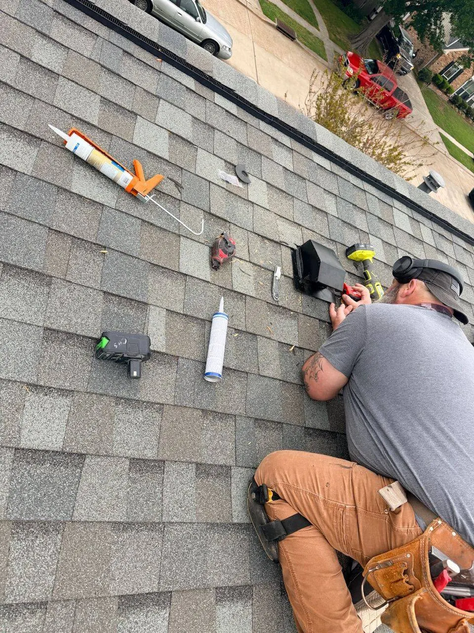Cajun Home Services roofer sealing vent boot on shingle roof with caulk gun in Louisiana neighborhood