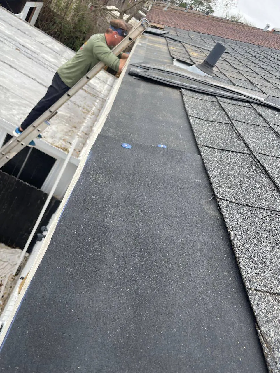 Synthetic underlayment being installed on roof deck before shingle installation on Louisiana home