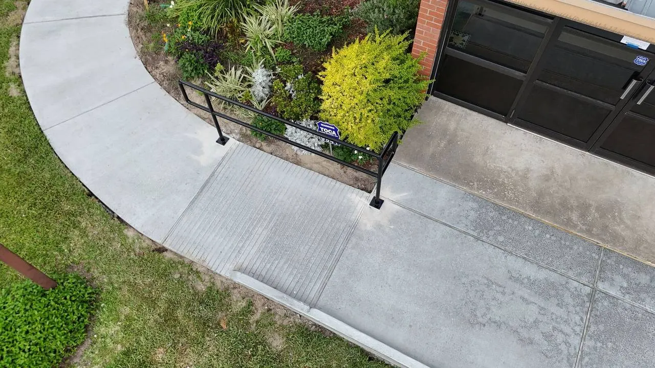 Detailed aerial view of broom finished ADA ramp transition and handrail installation at Jefferson Highway concrete replacement project