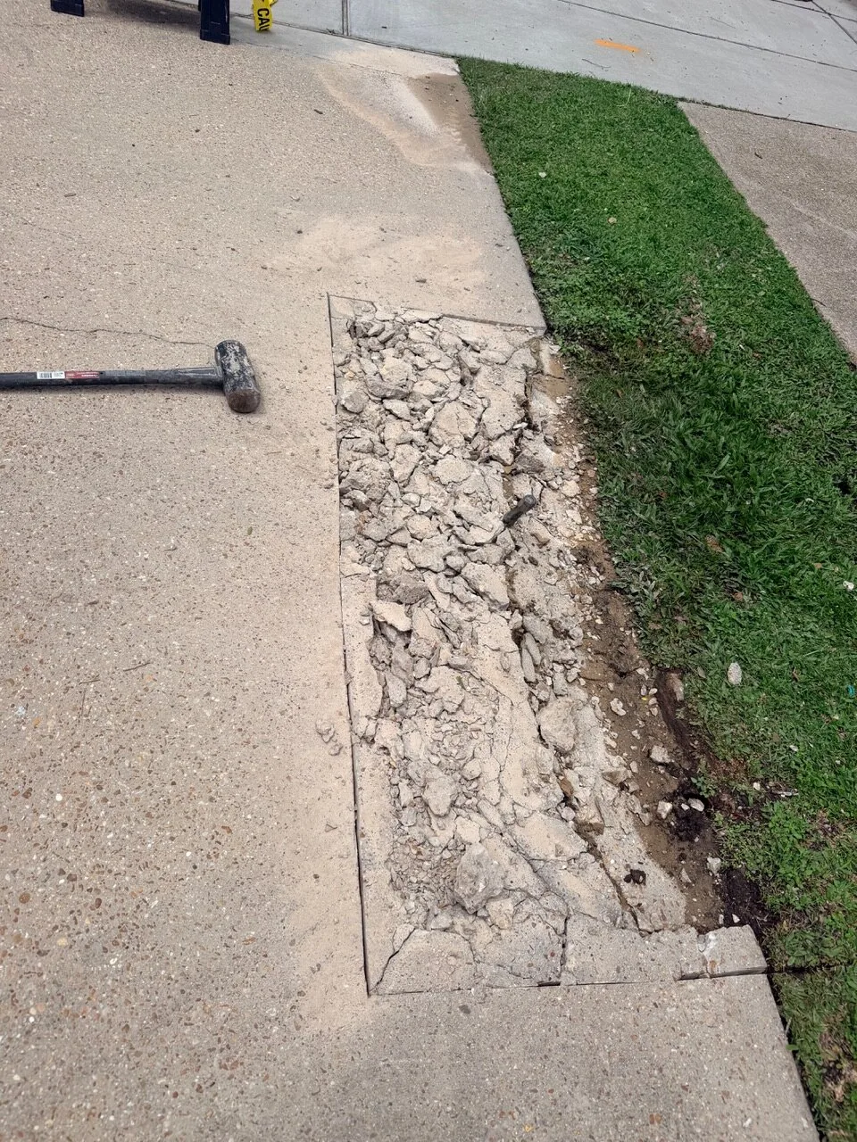 Sawcut concrete slab broken up with sledgehammer during damaged sidewalk demo for repeat customer on Jefferson Highway in Jefferson Parish Louisiana