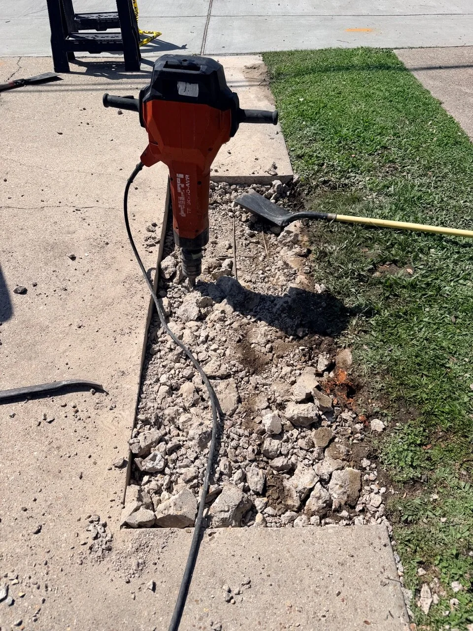 Hilti electric jackhammer breaking up reinforced concrete sidewalk slab during demolition on Jefferson Highway in Jefferson Parish Louisiana