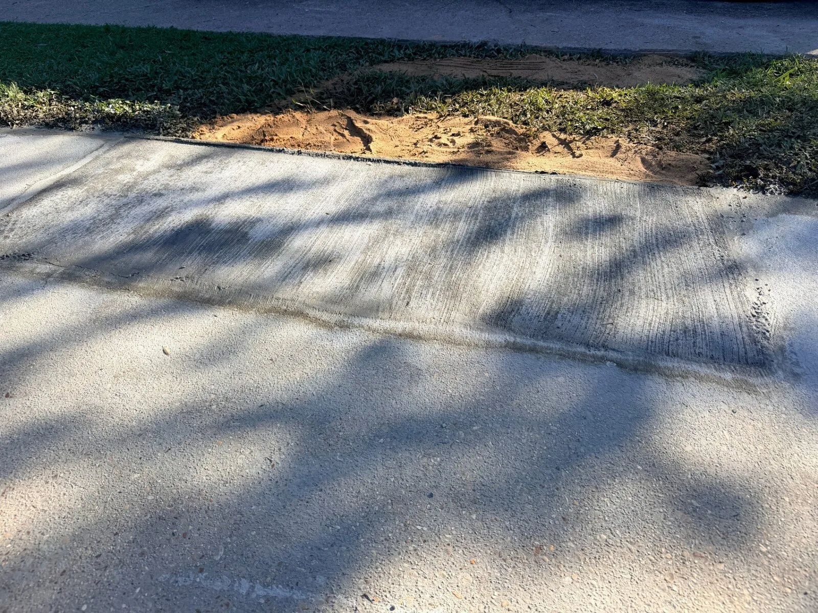 Finished broom-finished concrete sidewalk replacement with clean cold joint and backfilled edge on Jefferson Highway in Jefferson Parish Louisiana