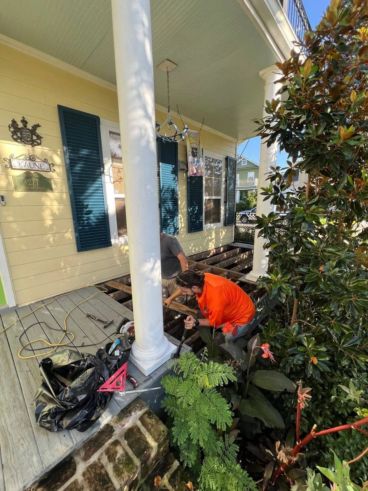Construction crew rebuilding historic porch deck on yellow Victorian home in Algiers Point, New Orleans