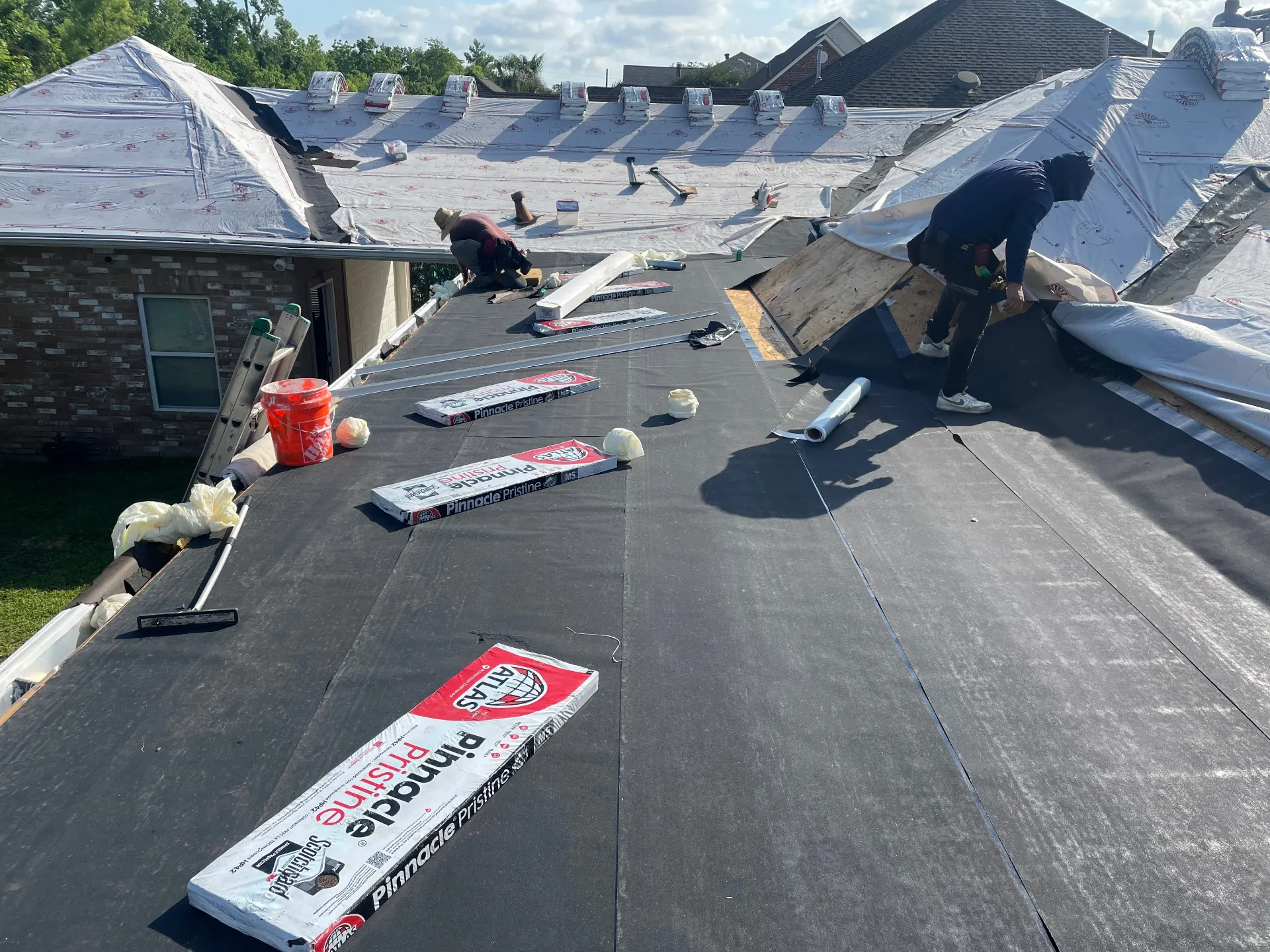 Atlas Pinnacle Pristine architectural shingle bundles staged across the underlayment on a Destrehan Louisiana shingle roof replacement jobsite