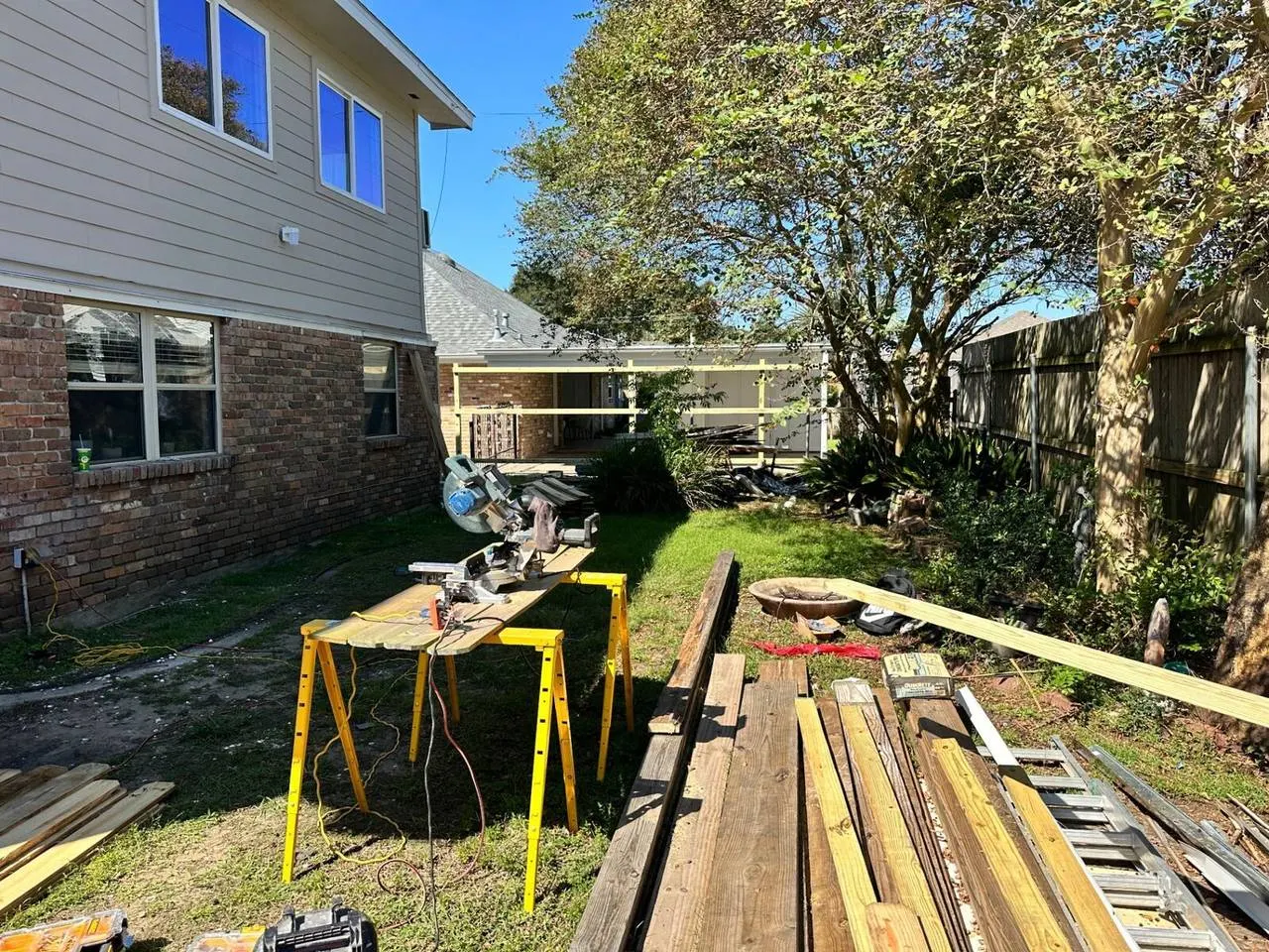 Backyard deck construction with lumber staging and miter saw in Metairie