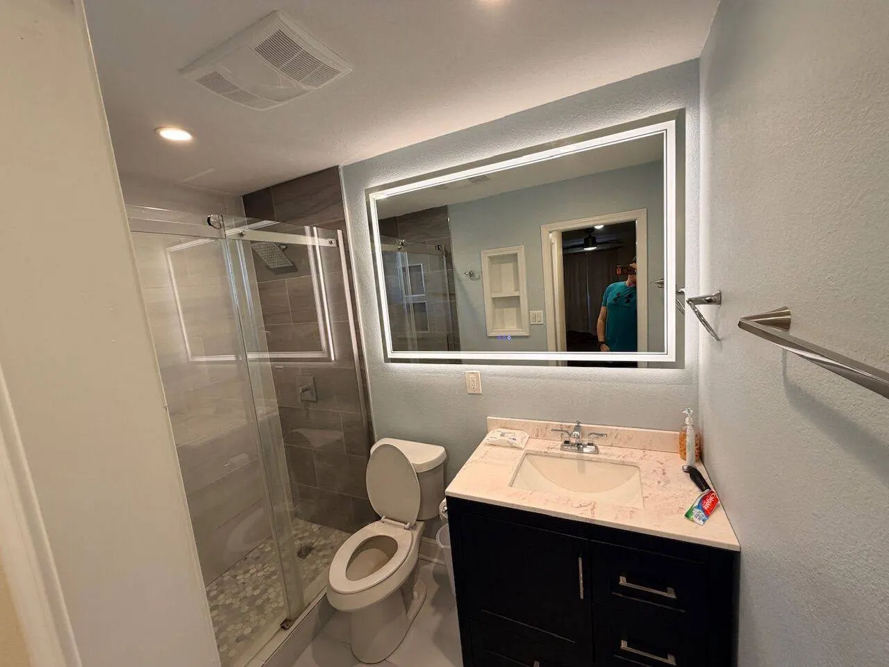 Completed bathroom with frameless glass shower, LED mirror, and marble vanity in Metairie LA