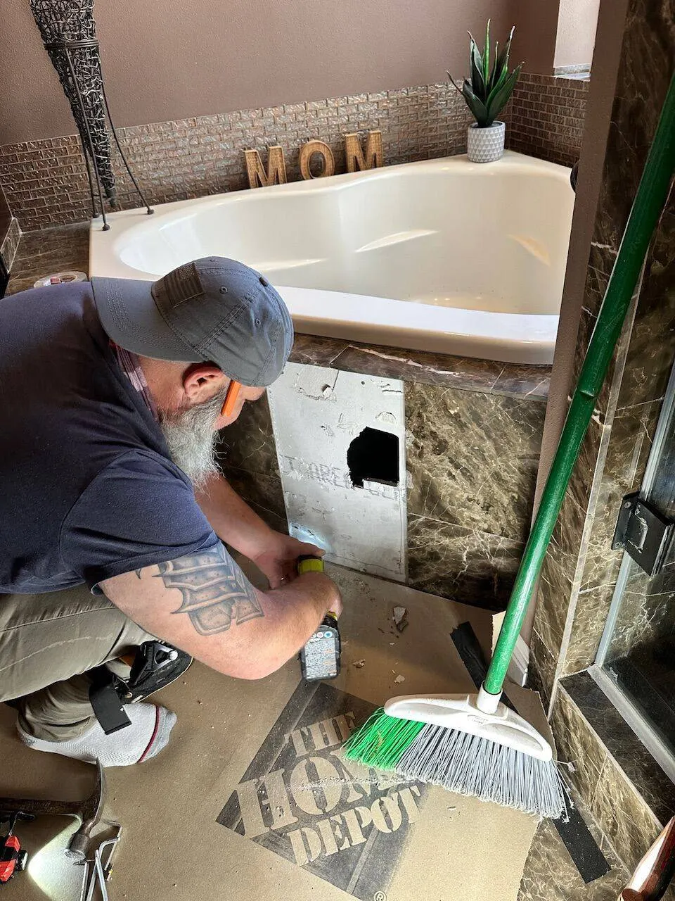 Contractor cutting access panel in marble tub surround for plumbing repair in Metairie