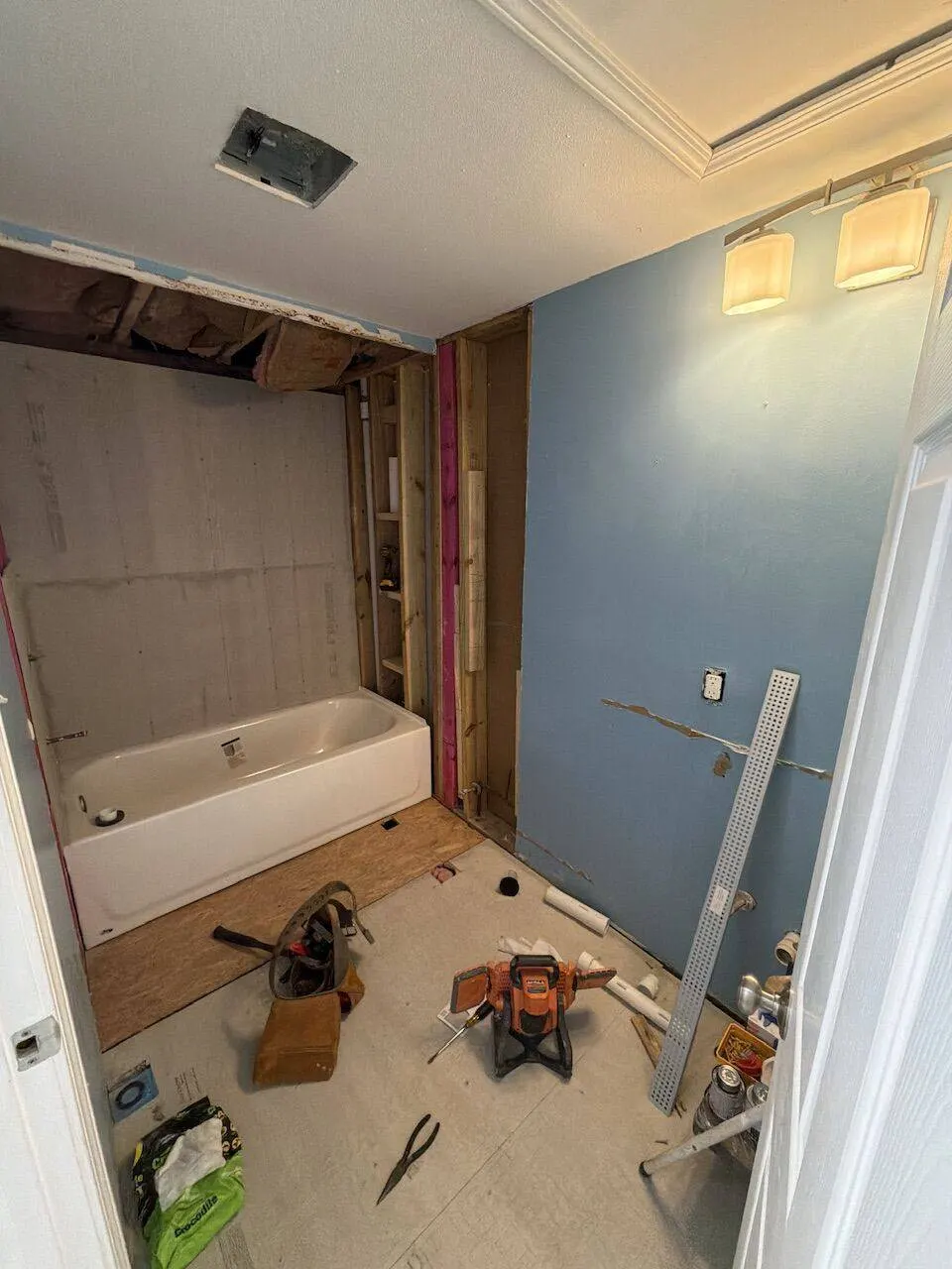 Bathroom demo in progress with tub set and wall framing exposed in New Orleans LA