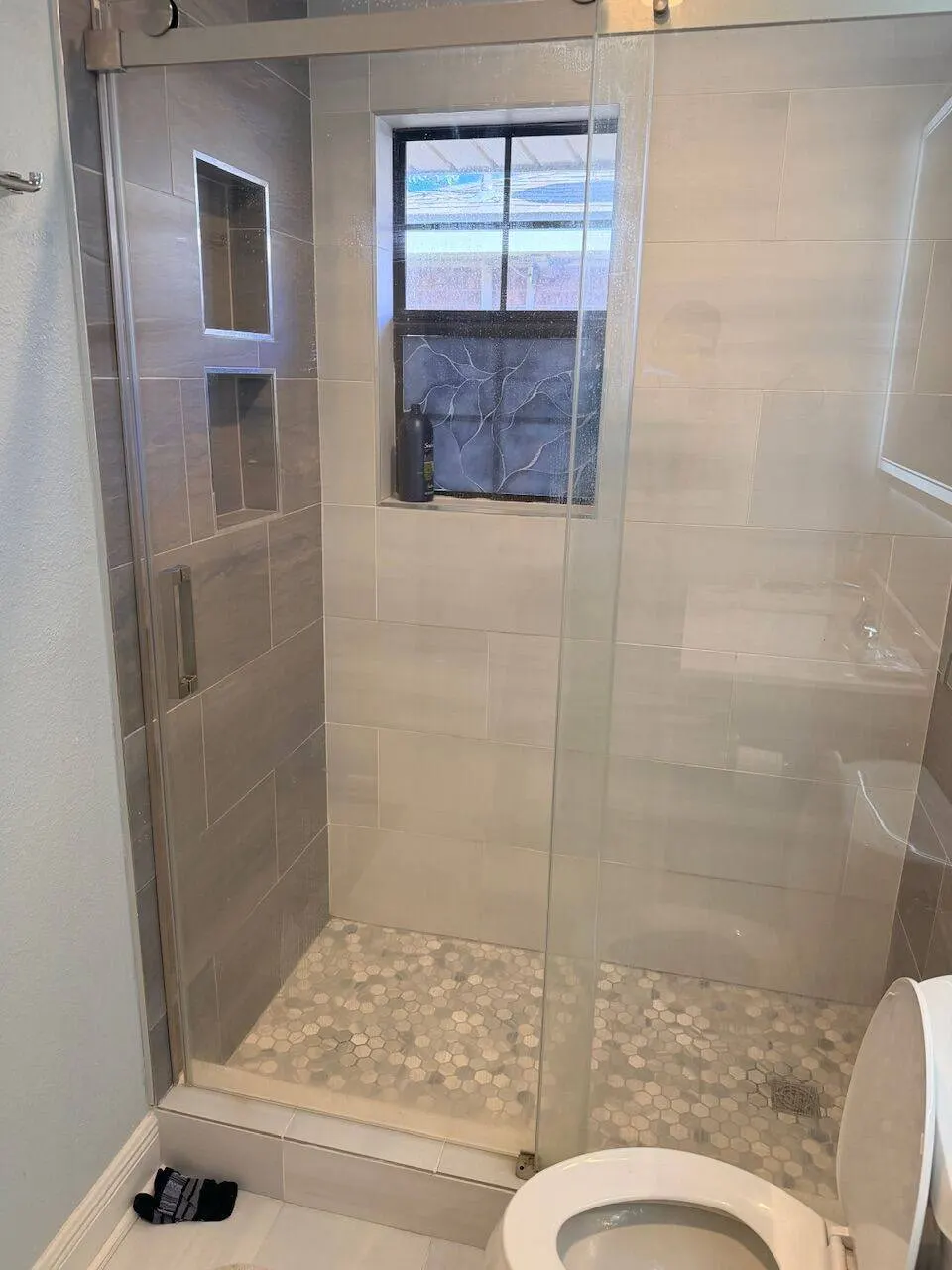 Frameless glass shower enclosure with hexagon mosaic floor tile and dual niches in Kenner LA