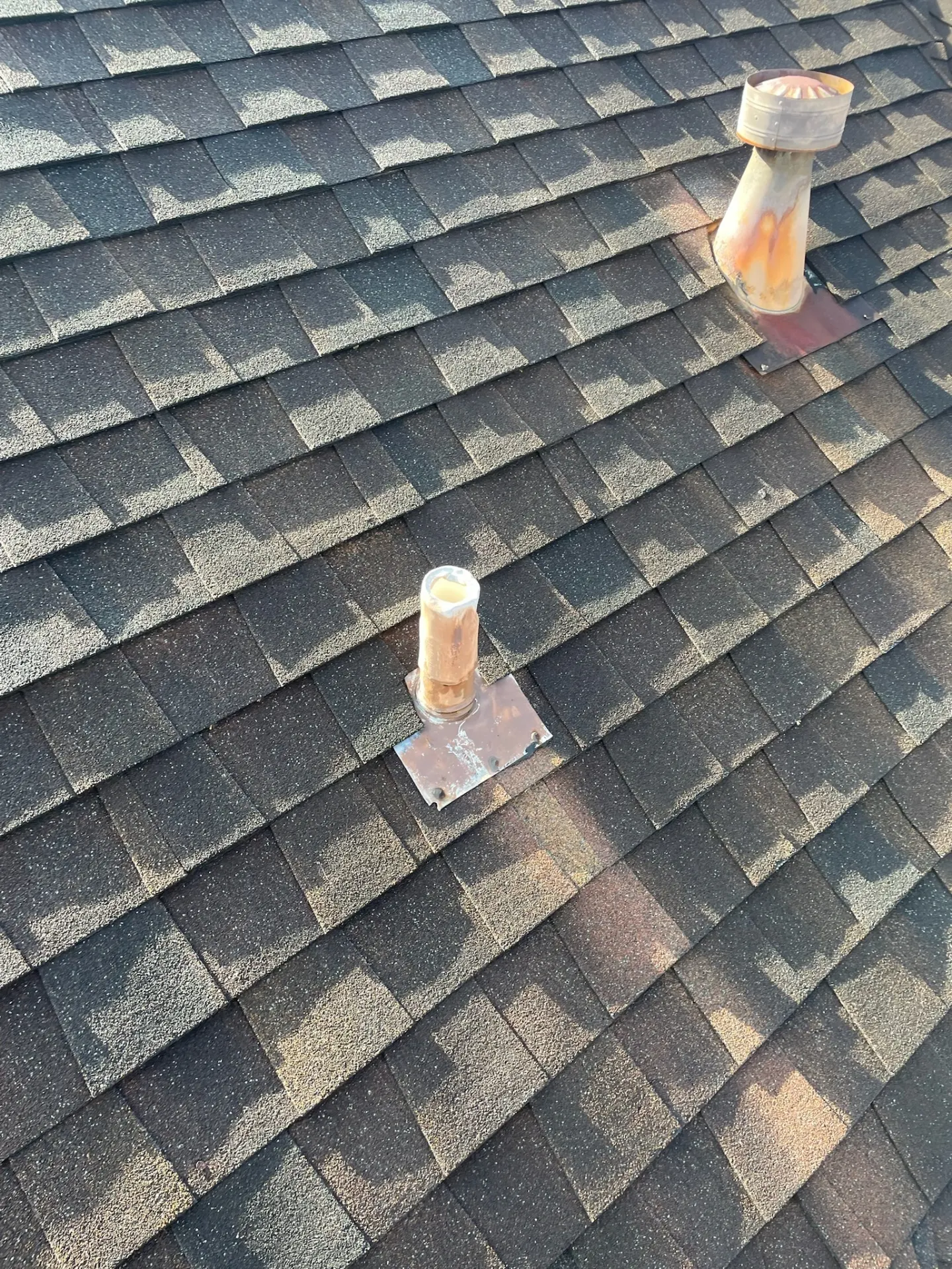 Close-up of severe granule loss and weathered asphalt shingles around aging plumbing vent boots on a Destrehan Louisiana home before re-roofing
