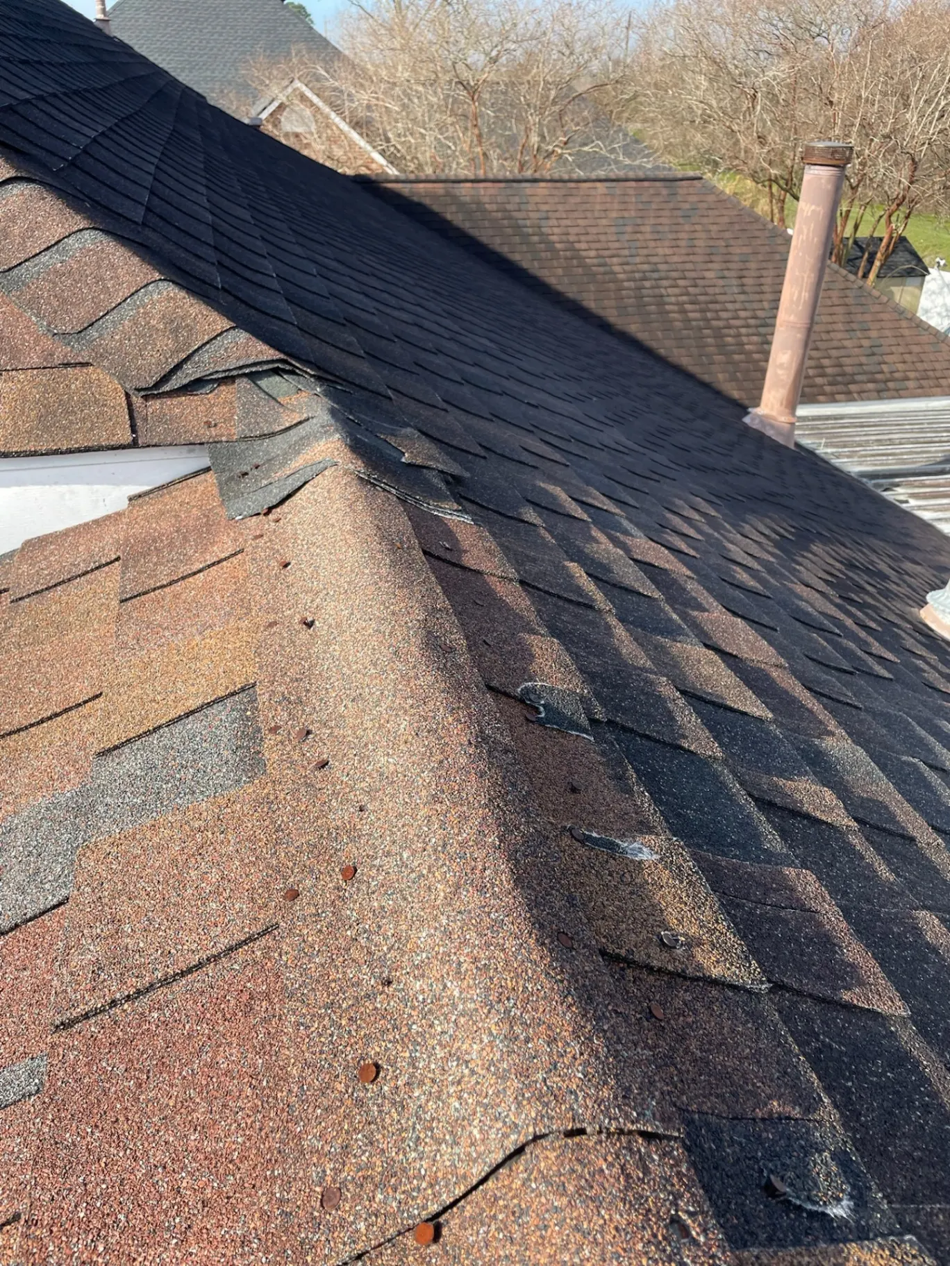 Close-up of brittle, lifting, granule-loss aged asphalt shingles on the Destrehan Louisiana home before re-roof replacement by Cajun Home Services