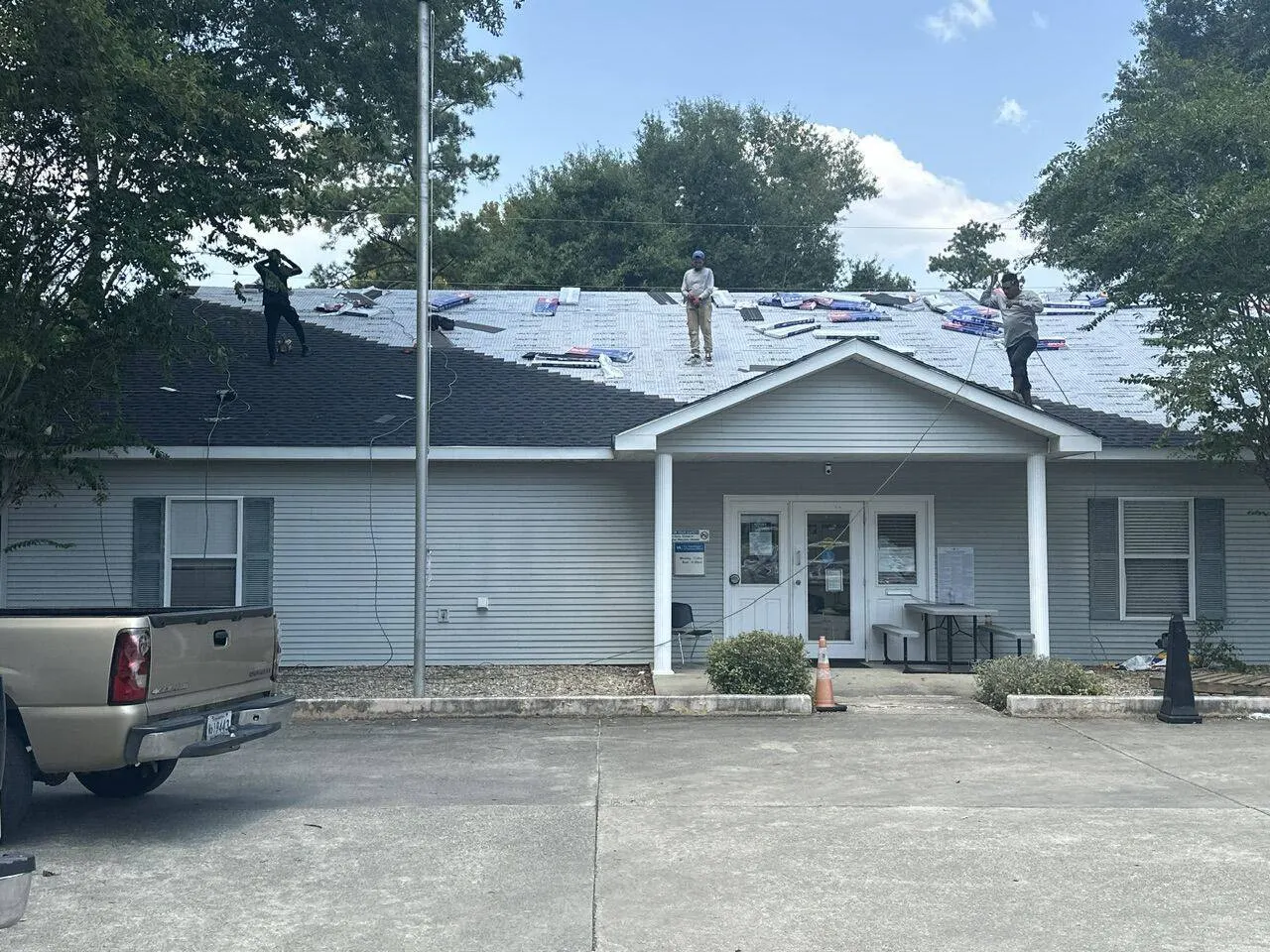 Commercial building shingle roof installation with crew staging materials in Louisiana