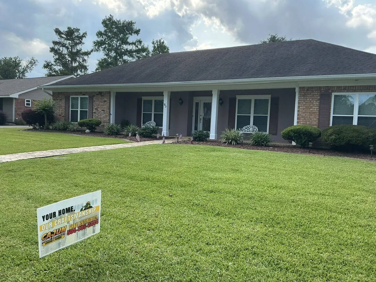 Finished residential reroof with Cajun Home Services yard sign in the front lawn