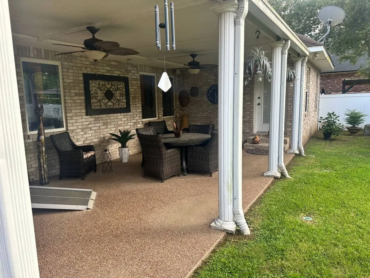 Completed covered patio with columns, ceiling fans and outdoor furniture in Destrehan, LA
